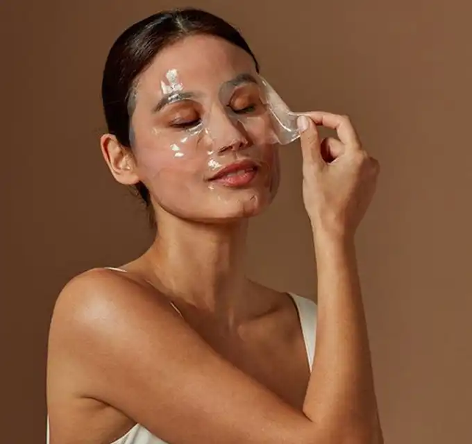 Woman peeling a hydrating mask sheet to restore moisture and glow